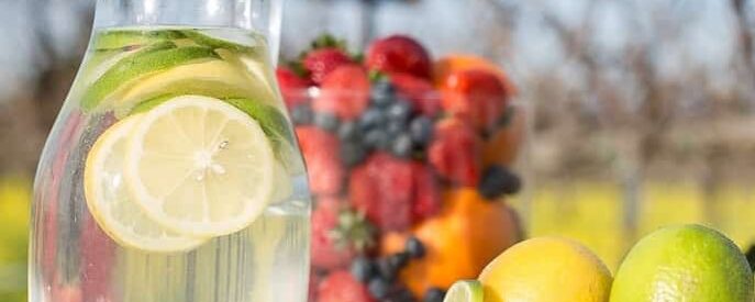 pitcher of water with low fodmap gluten free lime and low fodmap gluten free berries