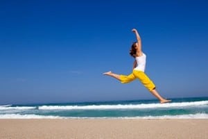 woman leaping on the beach. More energy and feeling better is one of the positive aspects of celiac disease diagnosis