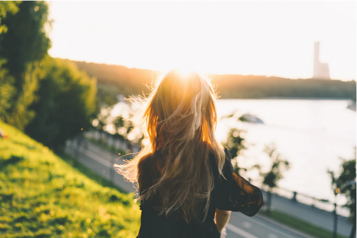 woman sitting on a hillside, soaking up sunshine and making vitamin D