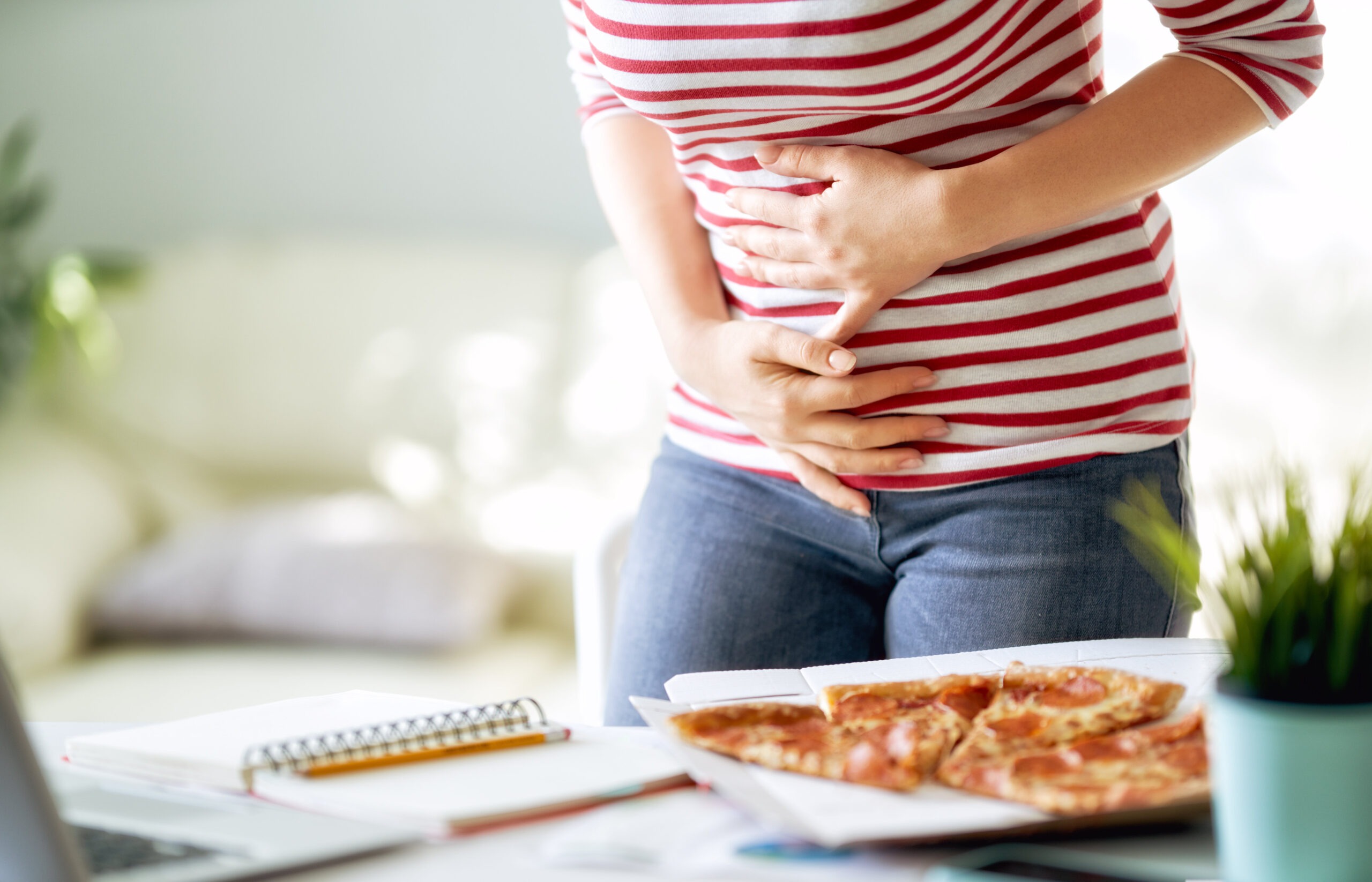pizza can cause mcas symptoms. Woman holding stomach after eating pizzA