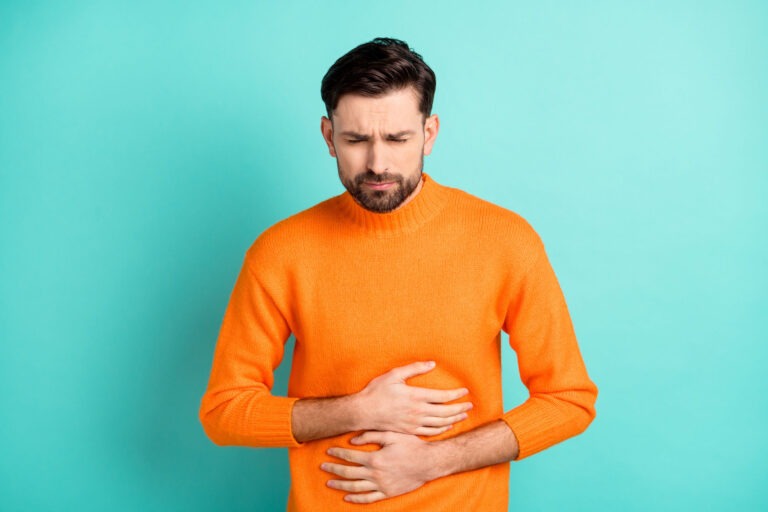 Man with beard in orange shirt-he has SIBO and is looking unwell. His sibo symptoms need a sibo test and sibo treatment