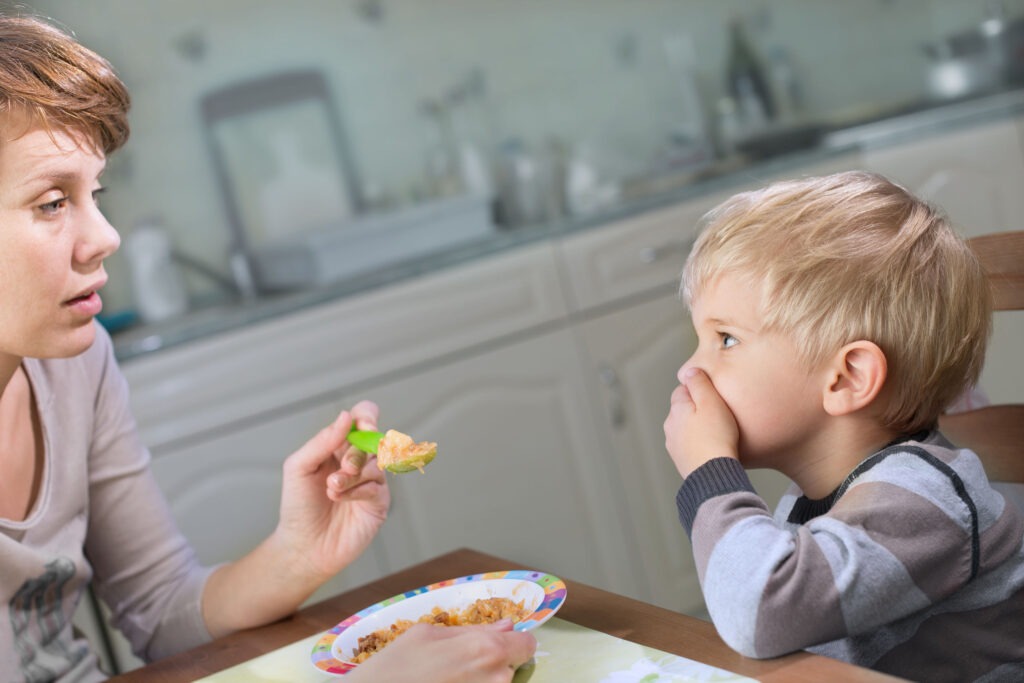 ARFID or ARFID Syndrome is not the same as a picky eater. This is a picture of a mom trying to feed a small boy but he is covering his mouth and refusing food.