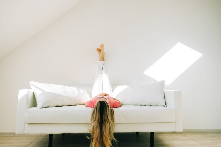 What is pots syndrome. A woman with POTS after covid is laying on a couch with her feet up in the air