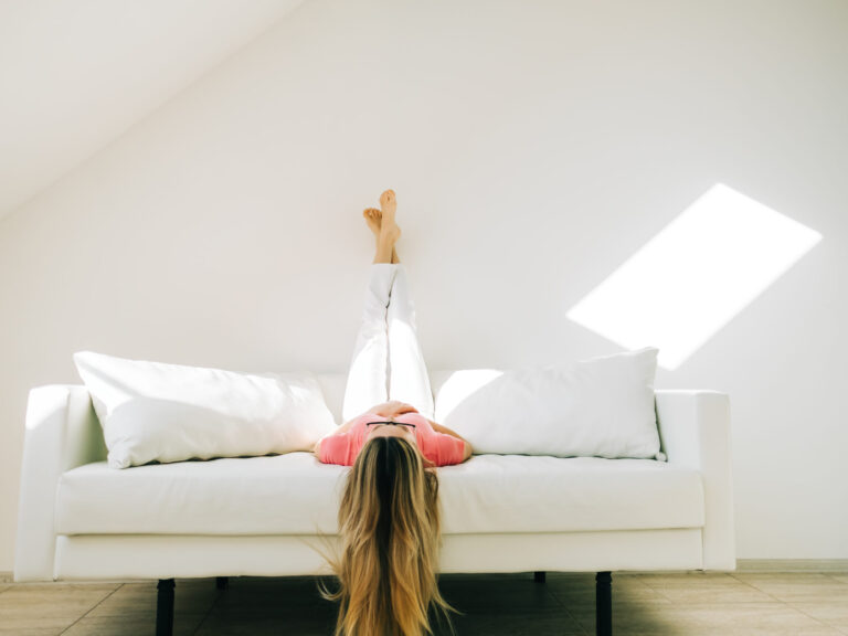 What is pots syndrome. A woman with POTS after covid is laying on a couch with her feet up in the air