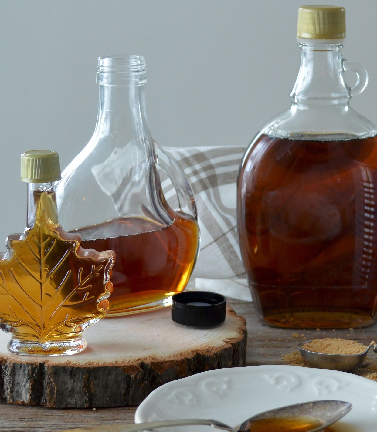 Three bottles of maple syrup which contain sucrose, a form of sugar that can make sucrose intolerance symptoms worse