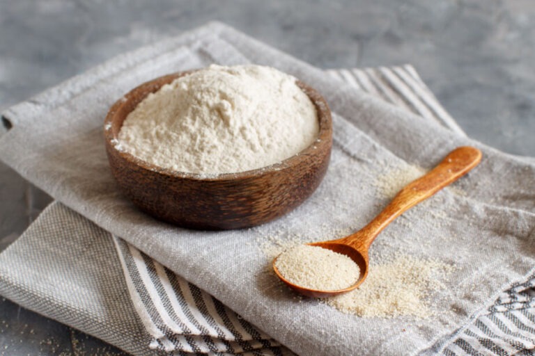 Fonio flour and a spoon with fonio grain all sitting on a linen napkin