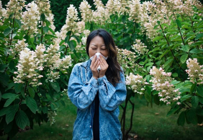 histamine intolerance symptoms in clude sneezing like the woman in the photo surrounded by flowers