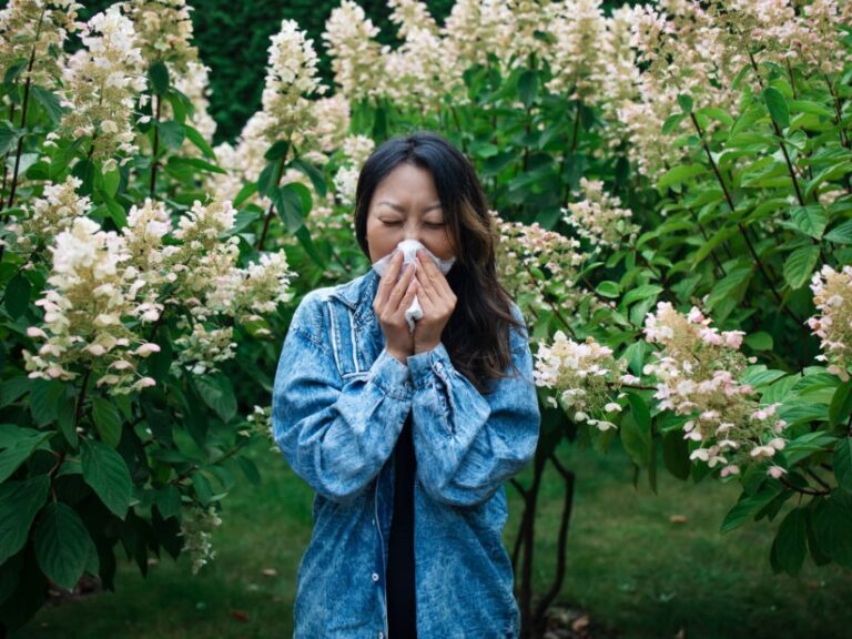 histamine intolerance symptoms in clude sneezing like the woman in the photo surrounded by flowers