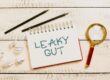 Image is words leaky gut on a notepad with a magnifying glass. A leaky gut diet differs depending on who you talke to