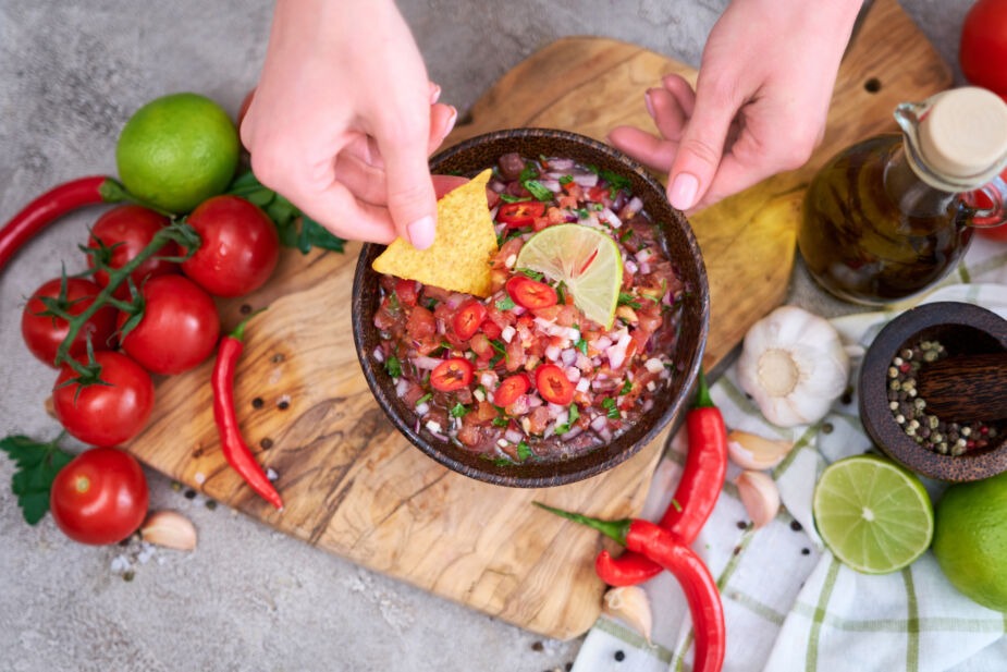 Bowl of salsa surrounded by tomatoes and limes, all of which are not well tolerated on a low histamine diet
