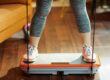 Woman standing on a whole body vibration plate to do exercise and experience whole body vibration therapy and vibration plate benefits. Warable vibration devices have benefits too