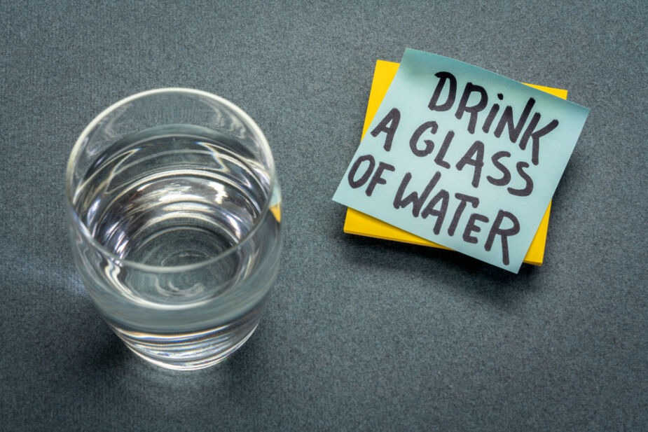 water for constipation. A picture of a glass of water with a post-it with the words " drink a glass of water"