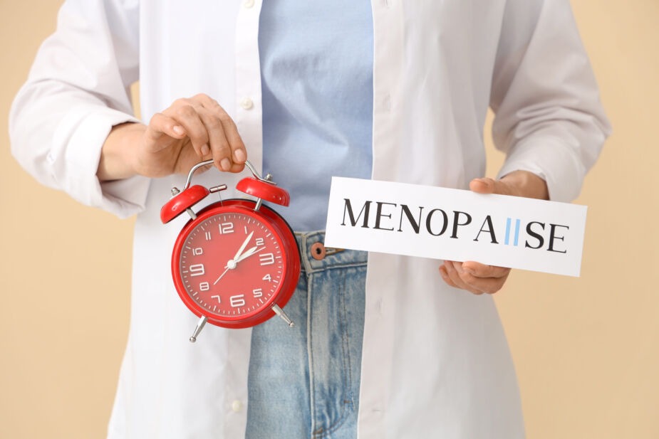 Menopause & IBS. Doctor holding a clock and sign with words menopause